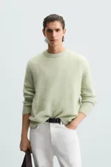Sweater verde claro tejido con lana y alpaca, de corte regular, cuello redondo y manga larga con terminaciones en rib.