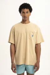 Remera color arena de corte holgado con bolsillo en el pecho y logo estampado en azul.