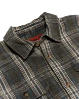 Camisa de franela a cuadros en tonos beige, gris y negro. Tiene cuello clásico, cierre con botones, dos bolsillos con solapa en el pecho y puños abotonados.