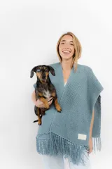 Ruana celeste tejida a mano en cinta de lana merino, con flecos en el borde inferior.