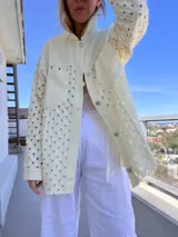 Sobrecamisa color manteca con calado geométrico, cuello camisero, cierre con botones y bolsillo de parche en el pecho.