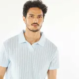 Remera polo celeste de punto gofrado con cuello clásico y mangas cortas.