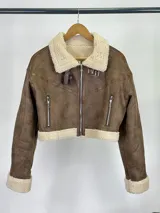 Campera de cuero marrón con interior de corderito y diseño corto, con cierre frontal y detalles en los puños.