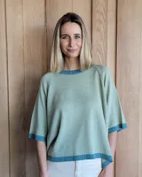 Buzo de punto color verde kiwi con cuello, puños y ruedo en azul.