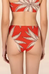 Calzón de bikini tiro alto con estampado floral en tonos naranja, beige y marrón. Presenta un aro dorado en el lateral.