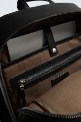 Mochila negra con acabado grabado, compartimento principal con cierre de cremallera, espacio interior para dispositivos electrónicos de hasta 13 pulgadas y bolsillo con cierre de cremallera. Dos bolsillos frontales con cierre de cremallera, parte posterior acolchada con bolsillo con cierre de cremallera y banda de sujeción para equipaje. Asa de mano y dos asas de hombro ajustables y acolchadas.