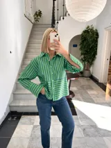 Camisa verde con rayas verticales azules, de corte recto y manga larga.