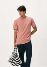 Camiseta blanca de algodón con cuello redondo y mangas cortas. Estampa rectangular con borde negro que contiene la frase "NATURAL ATMOSPHERE" en letras mayúsculas y una imagen de montañas y mar.