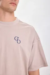 Camiseta manga corta color beige con estampa GO en el frente. Corte holgado y cuello redondo.