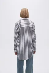 Camisa a rayas verticales grises y blancas, con cuello camisero, cierre frontal con botones, mangas largas con trabillas para enrollar y dos bolsillos de parche en el pecho.