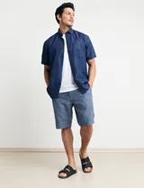 Camisa de manga corta azul con estampado de lunares blancos, cuello abotonado y bolsillo en el pecho.