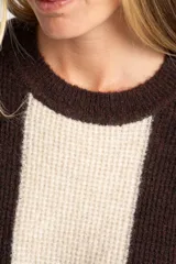 Sweater de tejido de punto grueso, con diseño de rayas verticales anchas en tonos marrón oscuro y negro. Presenta cuello redondo y mangas largas.