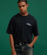 Remera negra de algodón con efecto desteñido (stone wash), corte boxy y manga corta. Estampa grande en la espalda con cinco calaveras amarillas y texto en blanco que dice "SAVAGE SQUAD" y debajo "WE WERE NEVER QUIET".