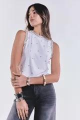 Musculosa blanca de punto con cuello redondo y sisas con apliques de strass y tachas plateadas.