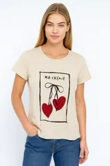 Remera color crema con estampado de cerezas rojas y texto "Ma Chérie" en recuadro negro.