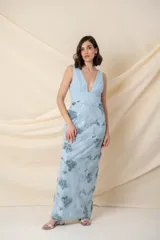 Vestido largo de fiesta color celeste, confeccionado en tul con corsé drapeado de escote profundo y falda bordada con apliques de flores.