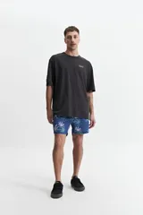 Short de baño azul con estampado de hojas de marihuana blancas y verdes. Tiene cintura elástica con cordón ajustable, dos bolsillos laterales y un bolsillo trasero.