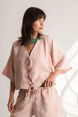 Blusa color crema confeccionada en lino, con mangas cortas, escote en V y lazos frontales.