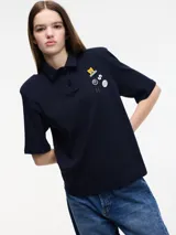 Remera tipo polo blanca de manga corta con hombreras y pins removibles en la delantera.