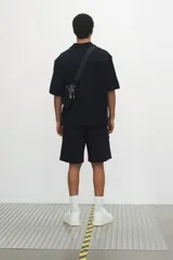 Short cargo negro de popelina de algodón, con cintura elástica ajustable con cordón, bolsillos laterales, bolsillos cargo con solapa y botón a presión en piernas y traseros, y aberturas laterales en el bajo.