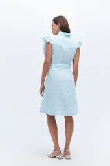 Vestido celeste de lino, corte a la rodilla, con cuello fruncido, volados en los hombros y lazo en la cintura.