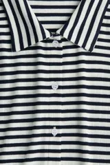 Camisa de manga corta en punto acanalado con rayas horizontales blancas y negras, cuello clásico y botonadura frontal.
