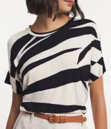 Blusa de viscosa color crudo con estampado abstracto en negro. Tiene cuello redondo y mangas cortas con recorte.