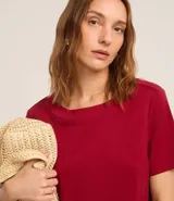 Vestido corto marrón, estilo camiseta, con escote redondo, mangas cortas y bolsillos laterales. El bajo es redondeado.