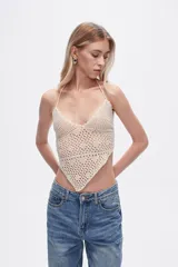 Top tejido al crochet color crema, con cuello halter y espalda descubierta.