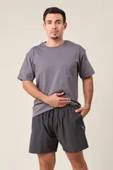 Bermuda deportiva gris oscuro de nylon, de corte suelto, con cintura elástica y cordón de ajuste. Cuenta con detalles de líneas en los costados y bolsillos con cierre.