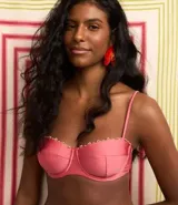 Top de bikini rosado con aro, modelo media taza, con tirantes finos ajustables y lazo en la espalda. Detalle de mini adornos de madera en el borde superior.