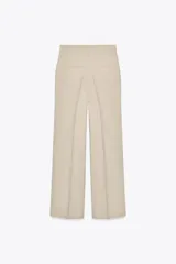 Pantalón color beige de tiro medio con trabillas, pliegues frontales y corte ancho.