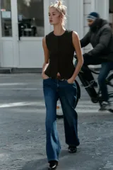 Top negro de punto, sin mangas, con cuello redondo. Presenta costuras marcadas en el frente y un bajo con abertura frontal que simula un peplum ajustado.