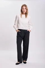 Pantalón de vestir negro, de corte carrot, con bolsillos laterales y traseros.