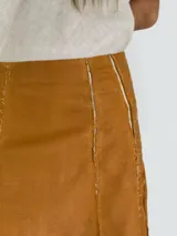 Pollera larga negra de corte amplio, con costuras verticales que simulan pliegues y terminaciones deshilachadas. Se combina con una musculosa negra de escote redondeado.