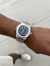 Reloj de pulsera Patek Philippe Nautilus con caja y brazalete de acero inoxidable, esfera azul con patrón horizontal en relieve y movimiento automático.