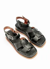 Sandalias negras de cuero con plataforma y tiras cruzadas en el empeine y tira con hebilla alrededor del tobillo.