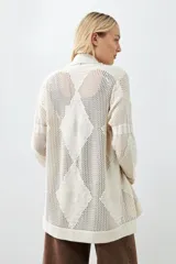 Ruana color beige claro con flecos en el borde inferior.