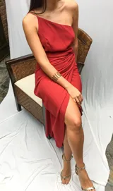 Vestido largo color rojo, de un solo hombro, con breteles finos y falda irregular con abertura lateral.