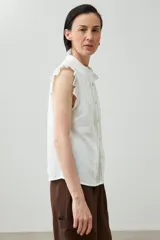 Camisa sin mangas color verde agua con cuello mao, cierre frontal con botones y detalle de puntilla en los hombros.