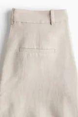 Pantalón de corte holgado color beige, confeccionado en mezcla de lino. Modelo de tiro alto con cierre y botón, bolsillos al bies, bolsillos insertados atrás y piernas amplias.
