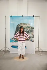 Remera de algodón y poliéster a rayas horizontales rojas y azul marino sobre fondo crudo. Tiene cuello tipo polo con botones, mangas amplias y corte oversized.