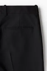 Pantalón de vestir negro de corte recto, confeccionado en mezcla de lino y algodón. Cuenta con cierre frontal con botón y gancho ocultos, bolsillos laterales y traseros ribeteados, pinzas y pliegues delanteros y traseros.