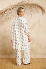 Camisa amplia de lino color blanco con bordado de flores negras, corte irregular con espalda más larga.