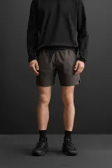Shorts deportivos color gris oscuro confeccionados en tejido técnico ligero y elástico con forro interior, cintura elástica ajustable con cordón, bolsillos laterales, bolsillo de seguridad en espalda con cierre de cremallera, bajo con aberturas laterales y detalle de logo estampado en pernera.