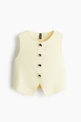 Chaleco color crema con cuello redondo y cierre frontal con botones metálicos.