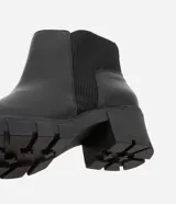 Bota Chelsea color negro, confeccionada en poliuretano, con detalle elástico acanalado en los laterales y suela track.