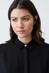 Camisa negra de manga corta con cuello clásico y cierre frontal con botones.
