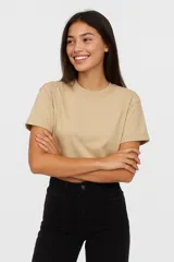 Remera cropped color beige de algodón, holgada y con cuello a la base.