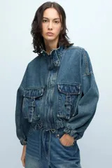 Campera de denim azul con corte deportivo, manga murciélago, elástico en la cintura, bolsillos dobles en el delantero y cierre frontal con tira cierre personalizado.